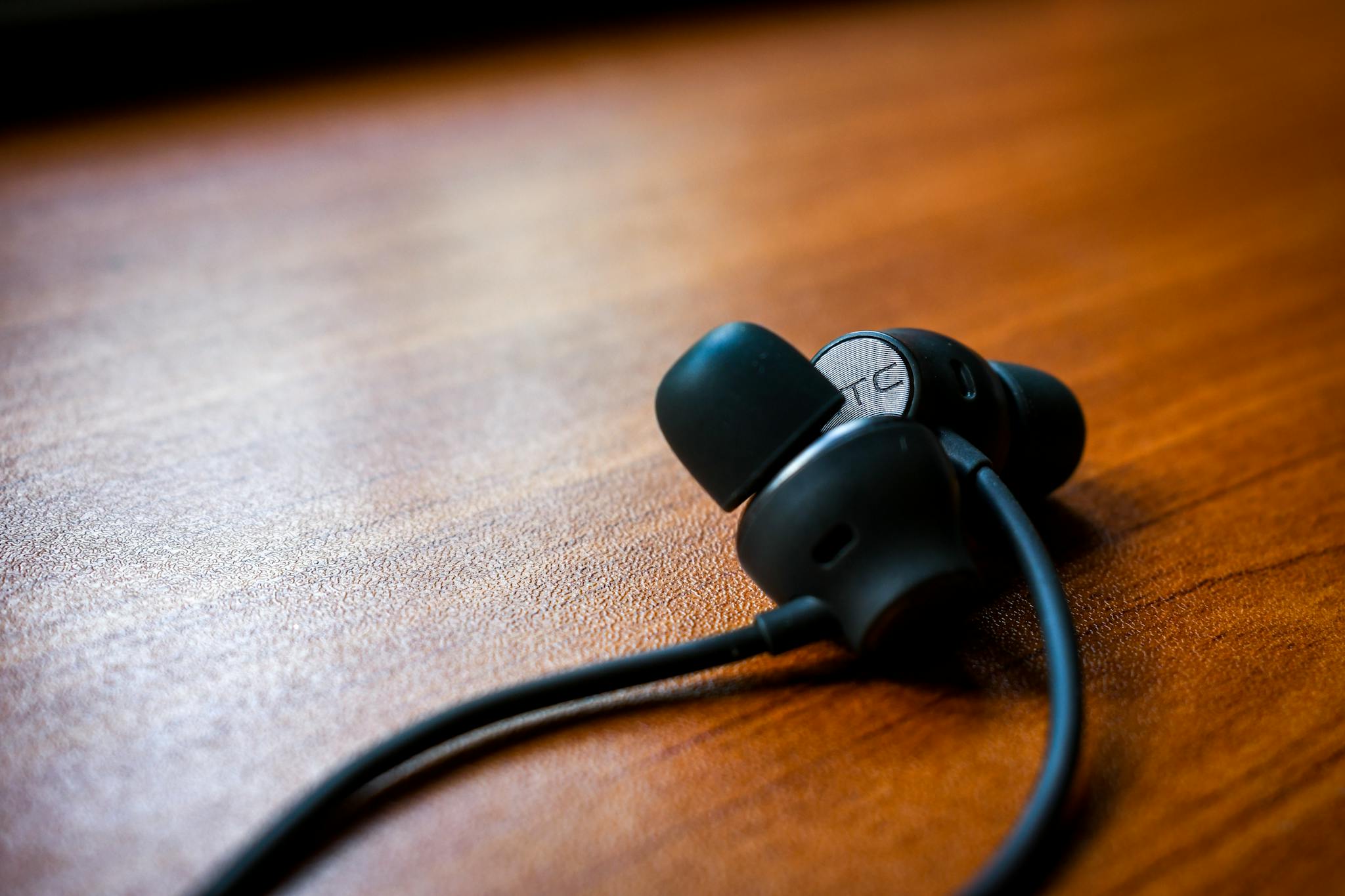 Detailed close-up of black earbuds resting on a polished wooden table, showcasing modern technology.